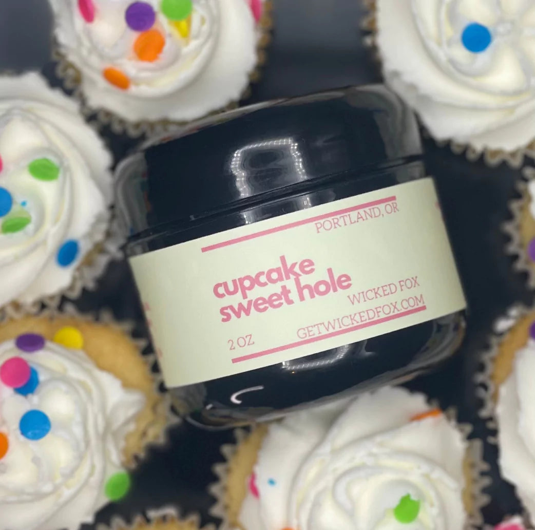 a jar of cupcake sweet hole by wicked fox is in a pile of lickable cupcakes. cupcake sweet hole is a flavored product to turn your butthole into better ass eating