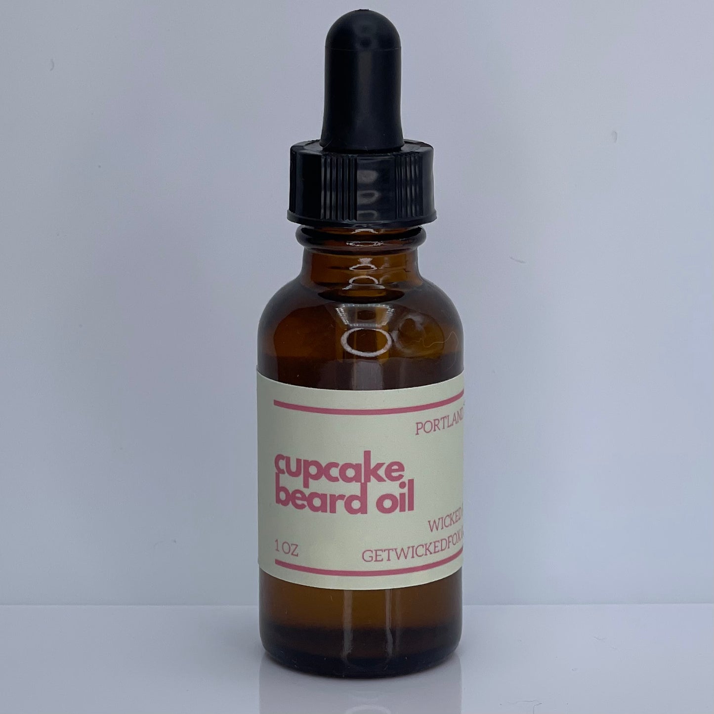 A bottle of Wicked Fox's Cupcake Beard Oil, enriched with natural ingredients, designed for the grooming needs of queer and trans men. Perfect for softening facial hair and reducing skin blemishes. Ideal beard care product for gay men shopping online.