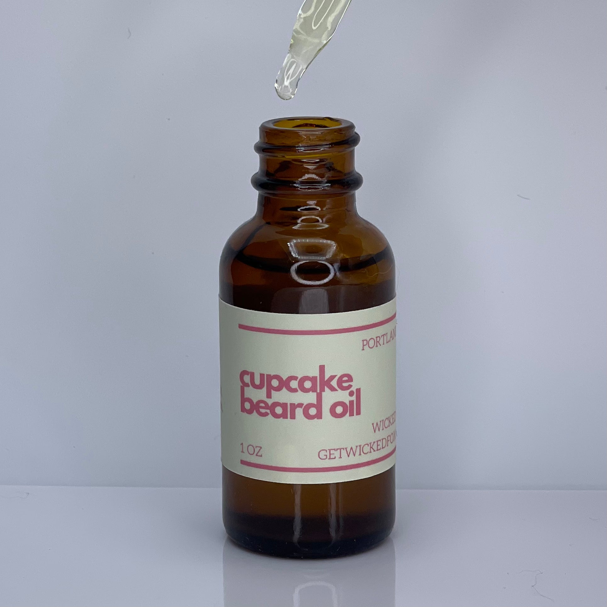 A bottle of Wicked Fox's Cupcake Beard Oil, enriched with natural ingredients, designed for the grooming needs of queer and trans men. Perfect for softening facial hair and reducing skin blemishes. Ideal beard care product for gay men shopping online.